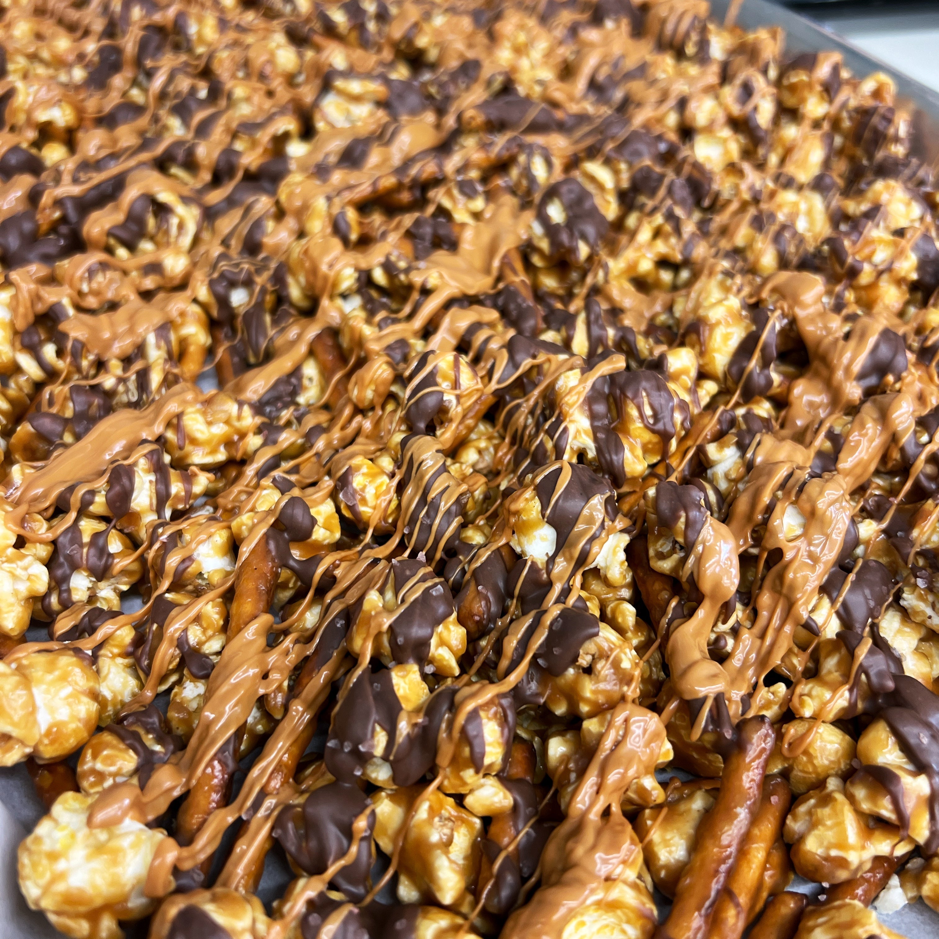 Our Salty Dog Popcorn with sea salt chocolate popcorn, salted caramel popcorn drizzled in sea salt chocolate and topped off with caramel pretzels. 